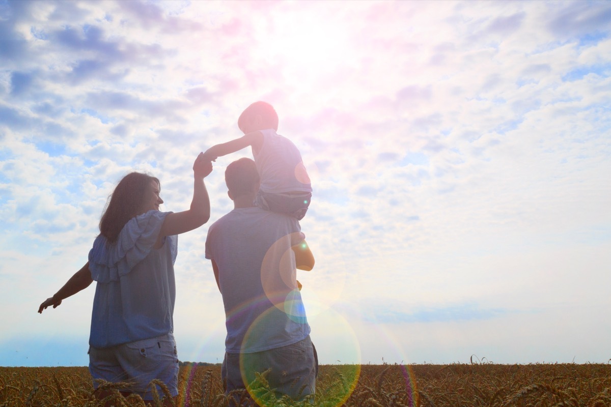 Family in field son on father's shoulders