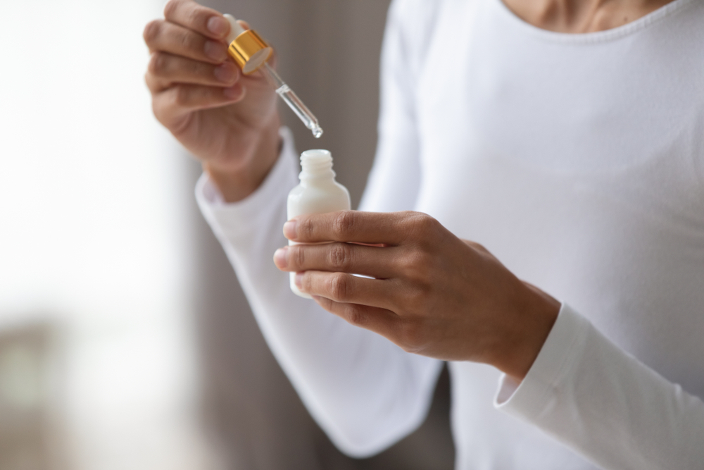 A closeup of a person's hands holding a bottle of skincare product