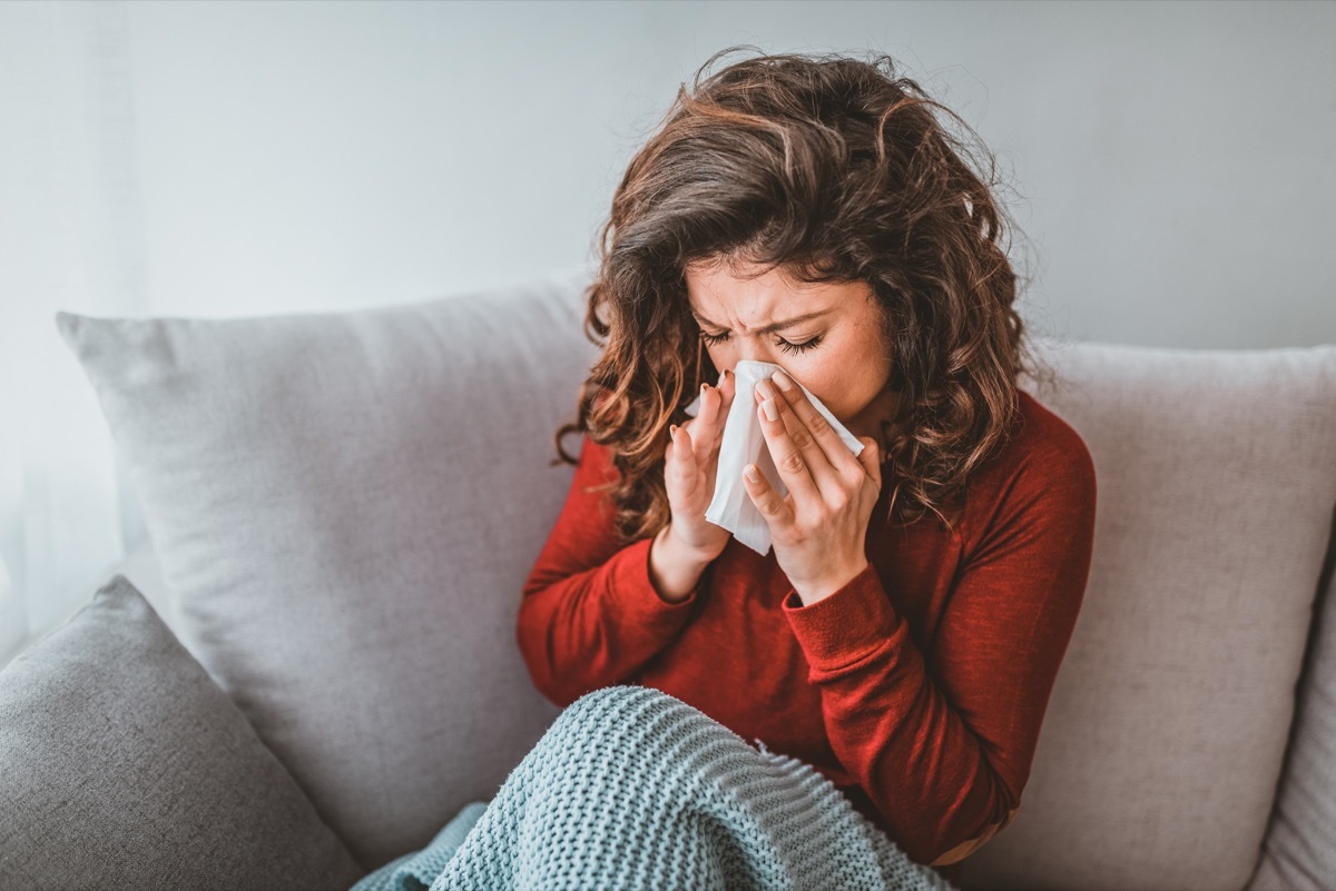 Portrait of woman with allergy blowing her nose