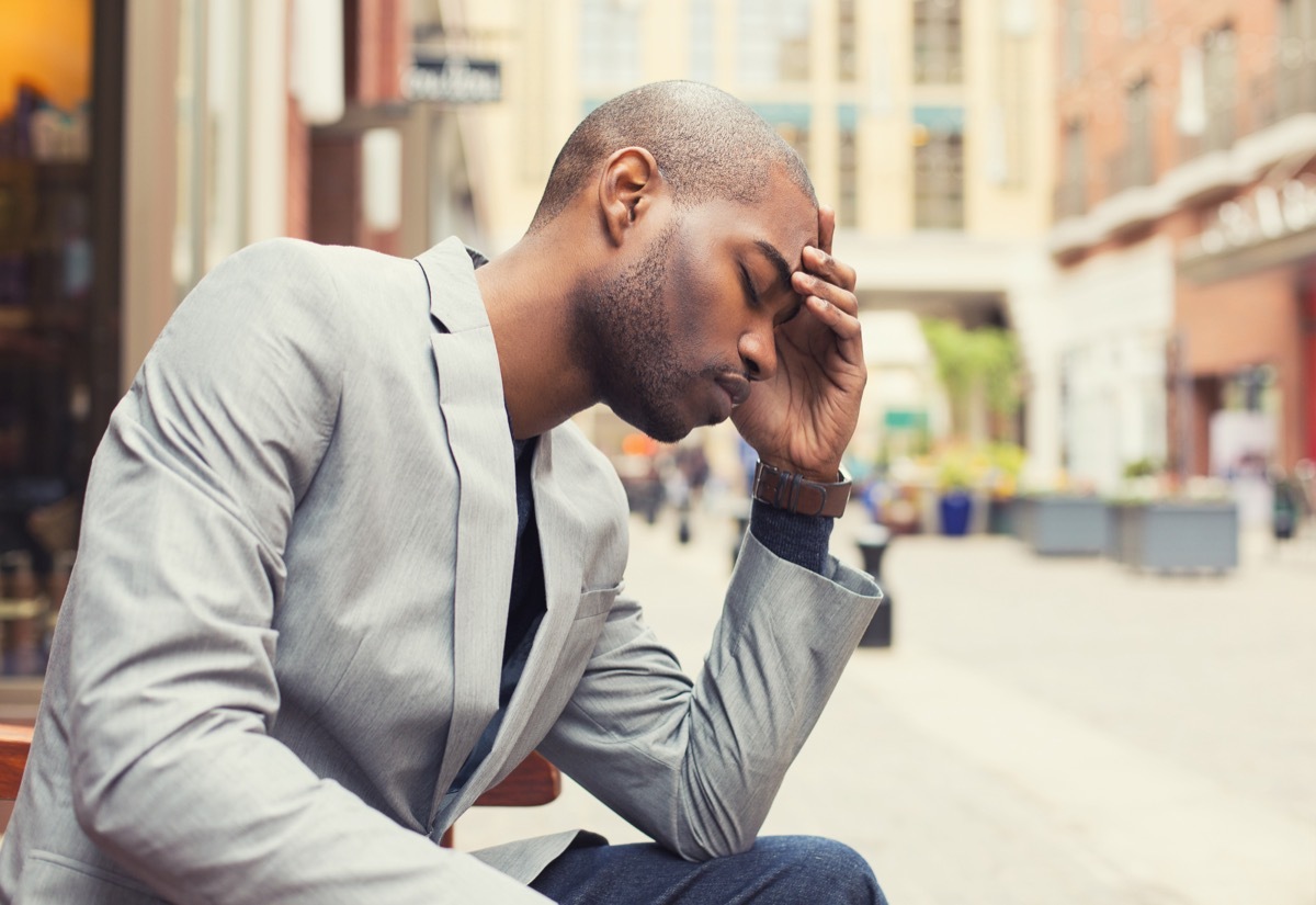 man holds head, health risks for men over 40