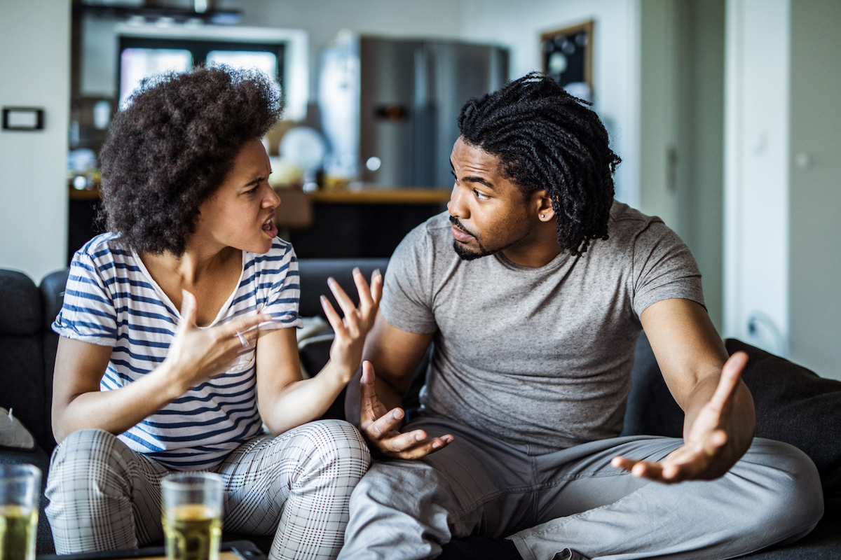 Frustrated looking young couple arguing on their couch