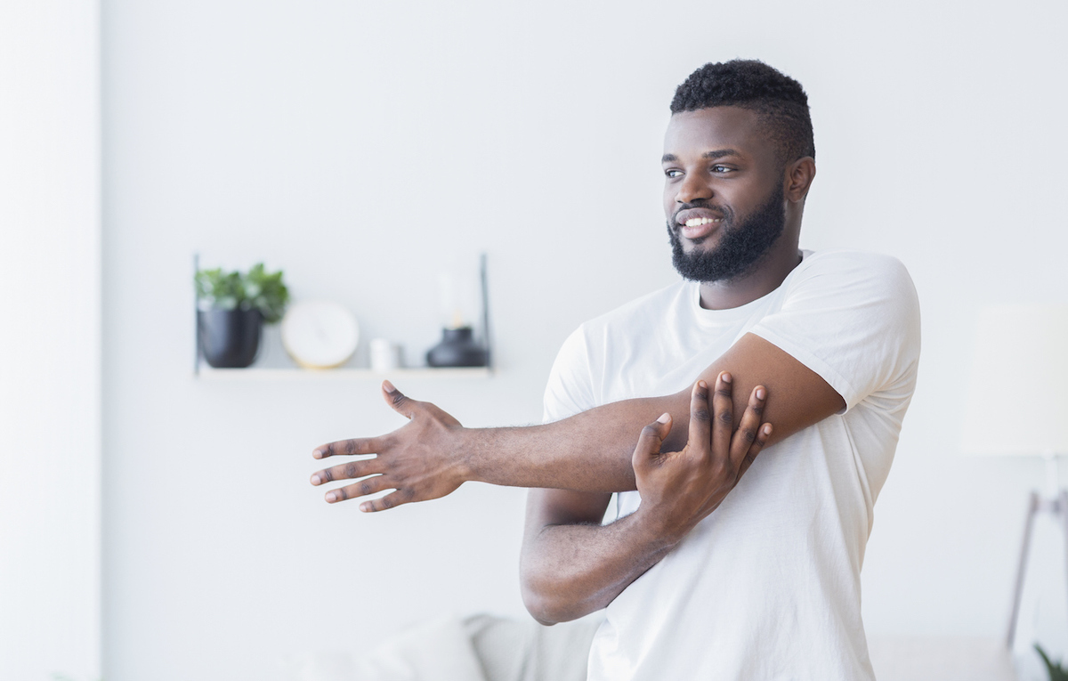 Young man training and stretching arm at home