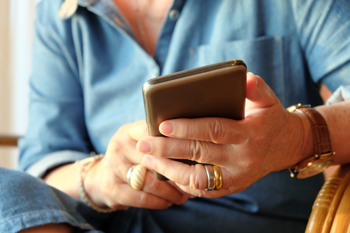 closeup of hands of older woman using smart phone