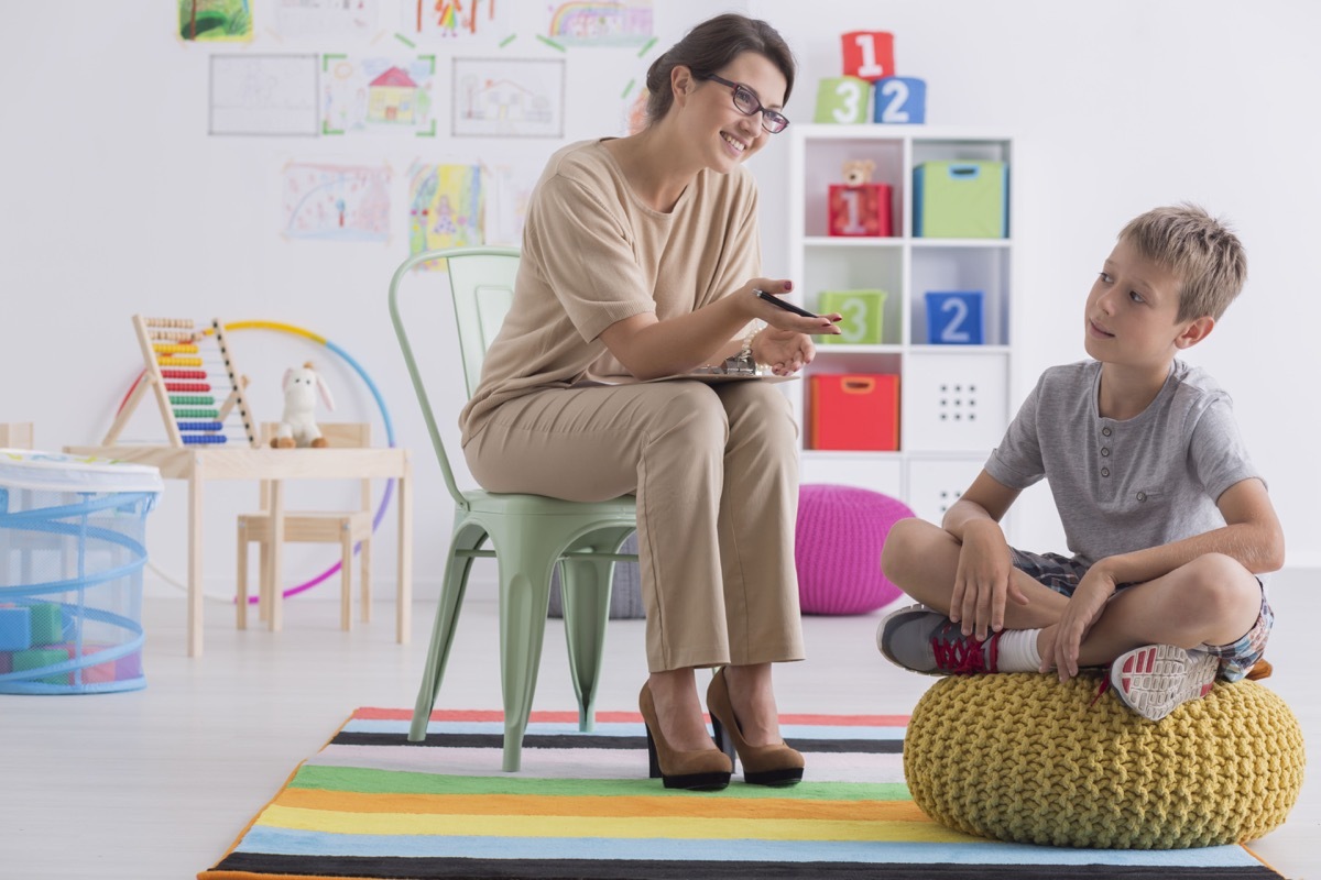 therapist sits in chair as young boy sits on ottoman during therapy session, prepare children for divorce