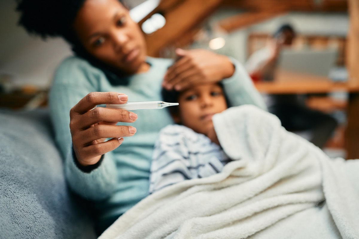 mother using thermometer and measuring temperature or her sick son at home.