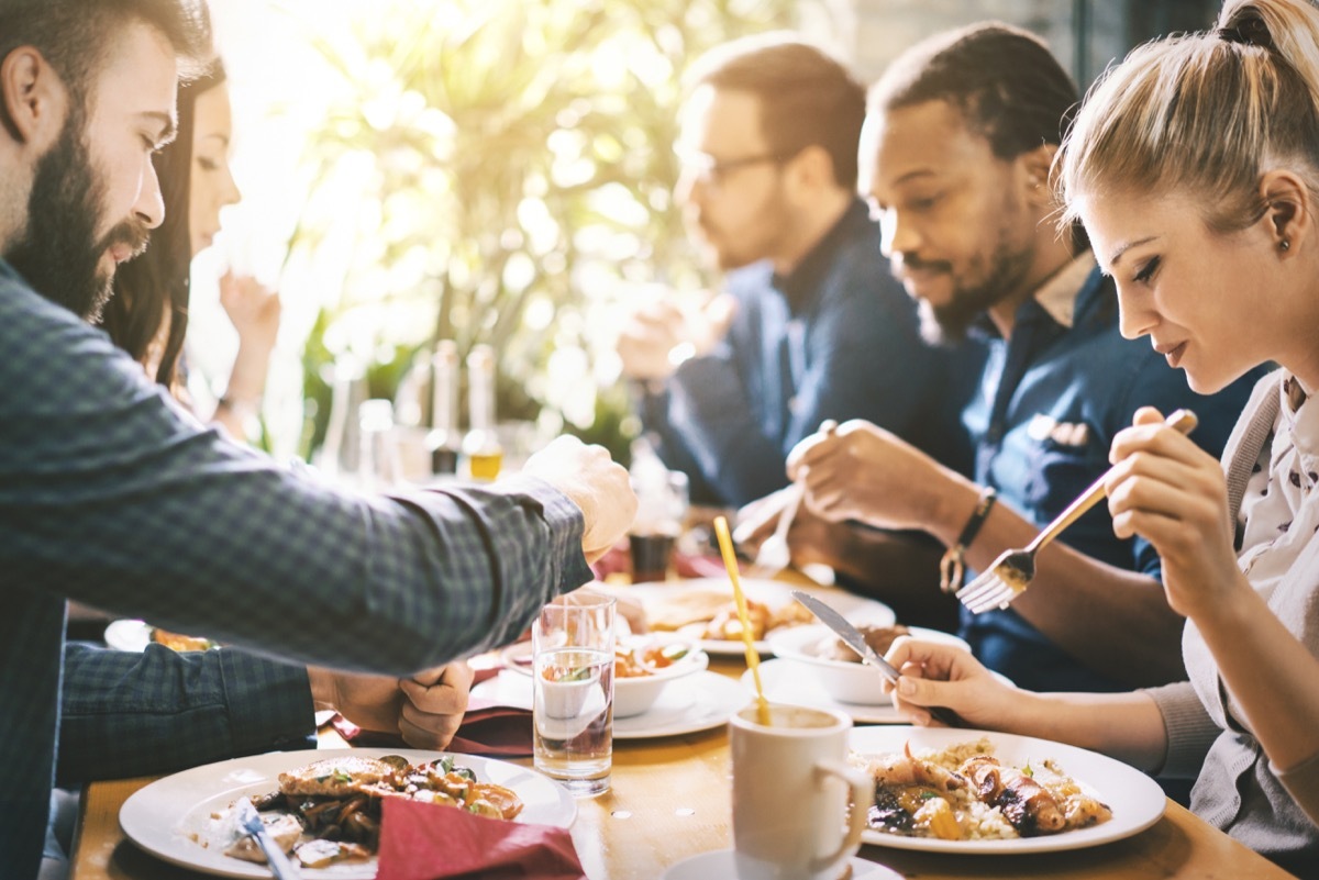 Closeup side view of group of mid 20's employees taking a lunch break at a restaurant.