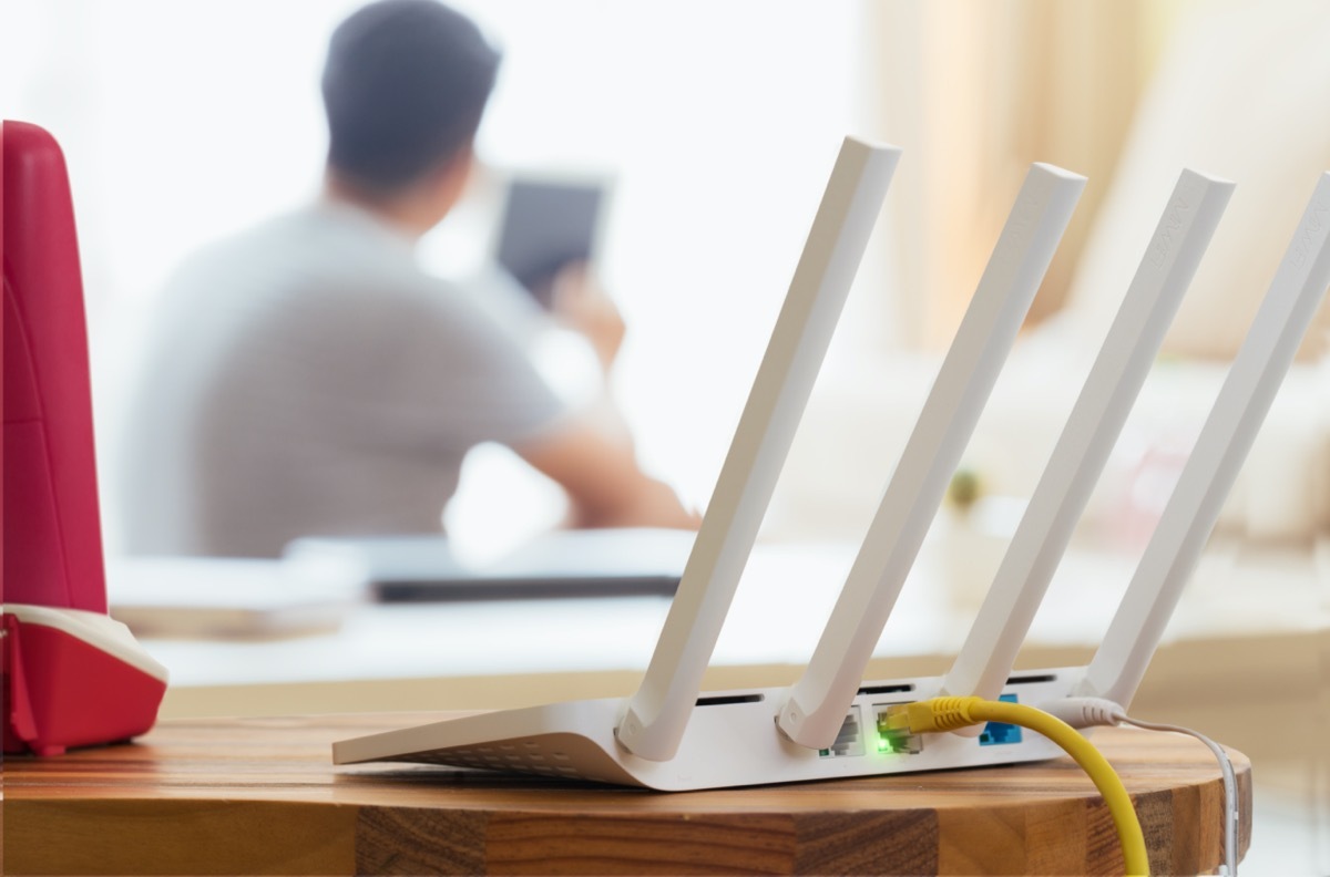 closeup of a wireless router and a man using smartphone on living room at home ofiice