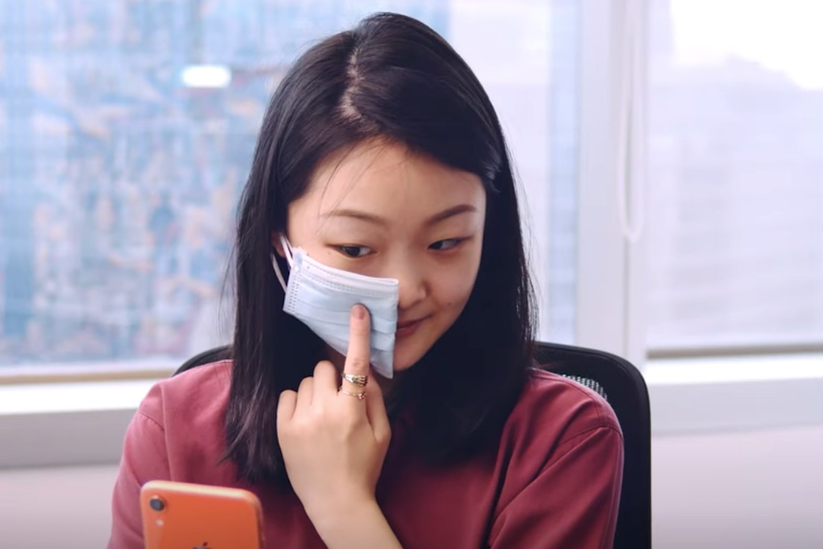 woman holding up face mask on left side of face