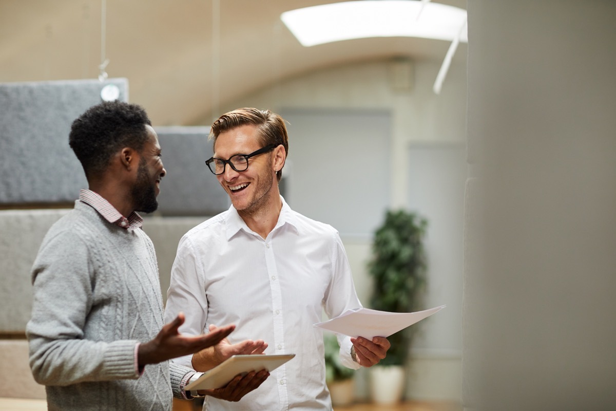 young white man and black man talking at work