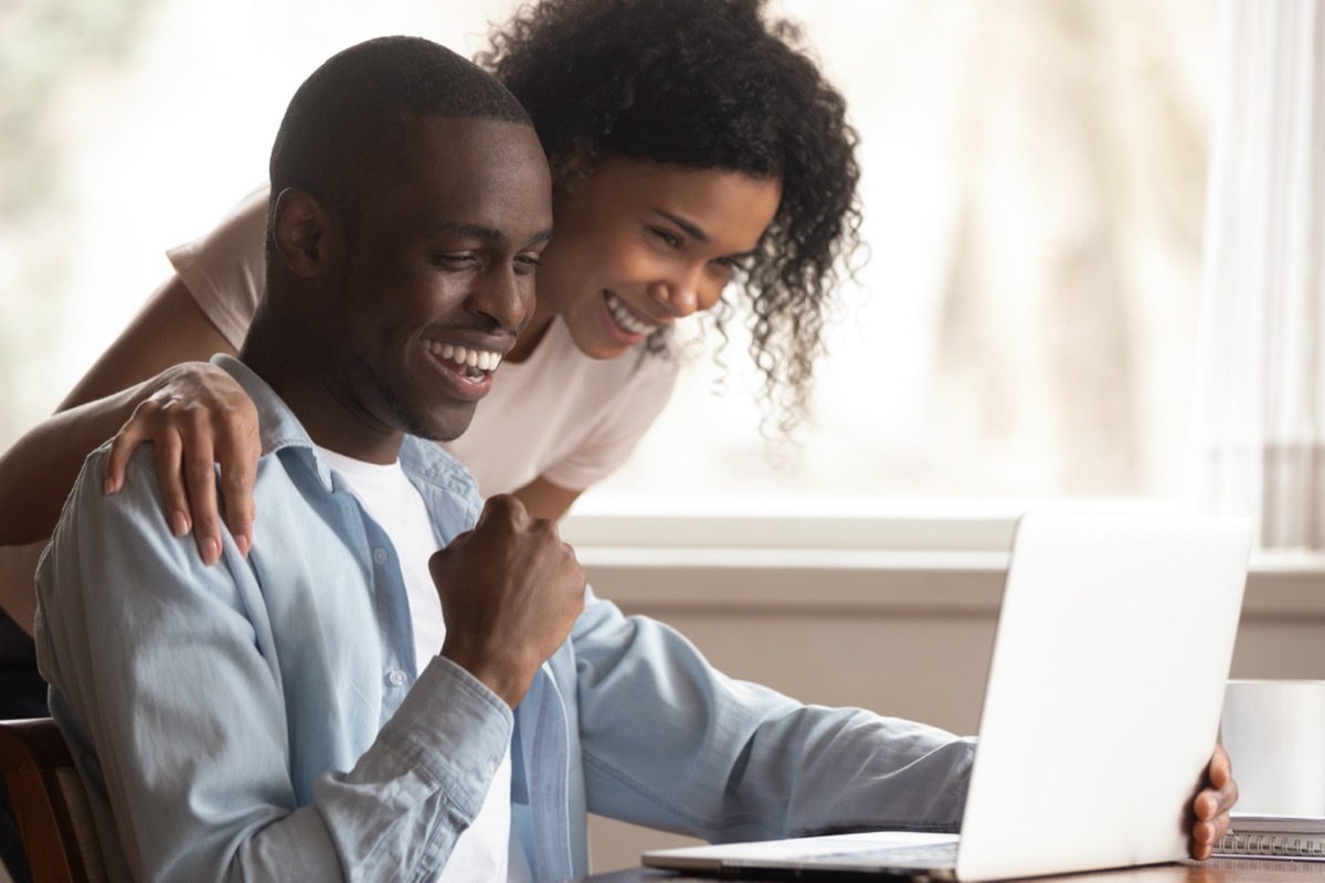 happy young couple looking at computer while smiling