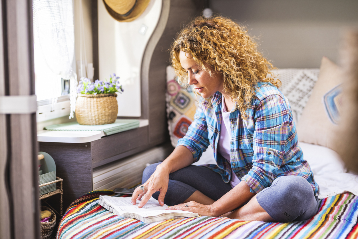 A woman sitting on a bed inside a tiny home or camper van