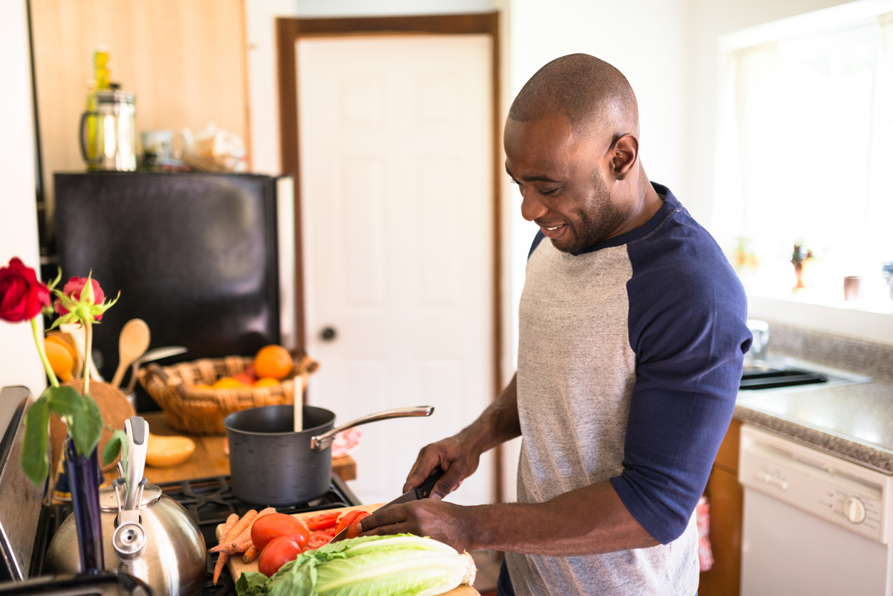 A man standing in his kitchen cooking food