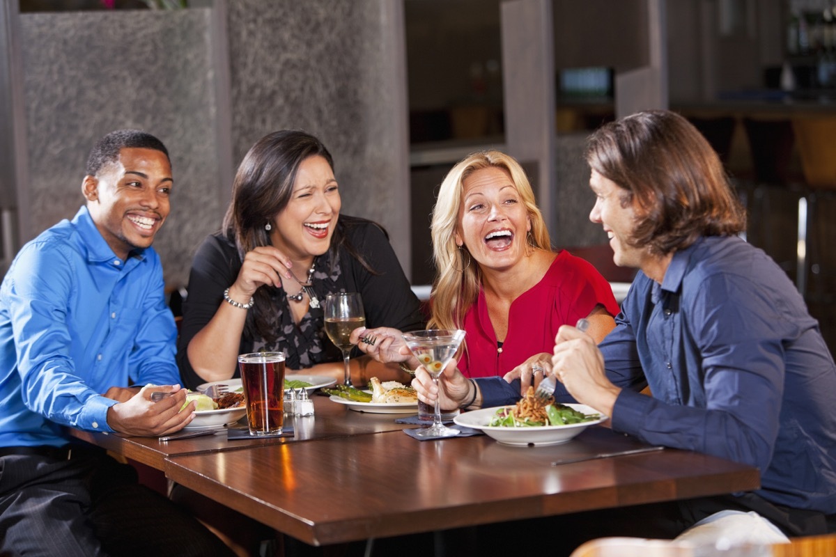 two couples sitting around a table and laughing on a double date