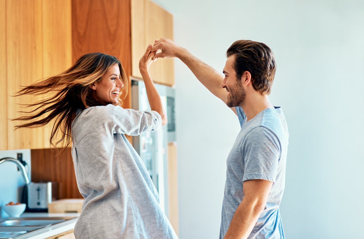 Shot of a happy young couple dancing together at home