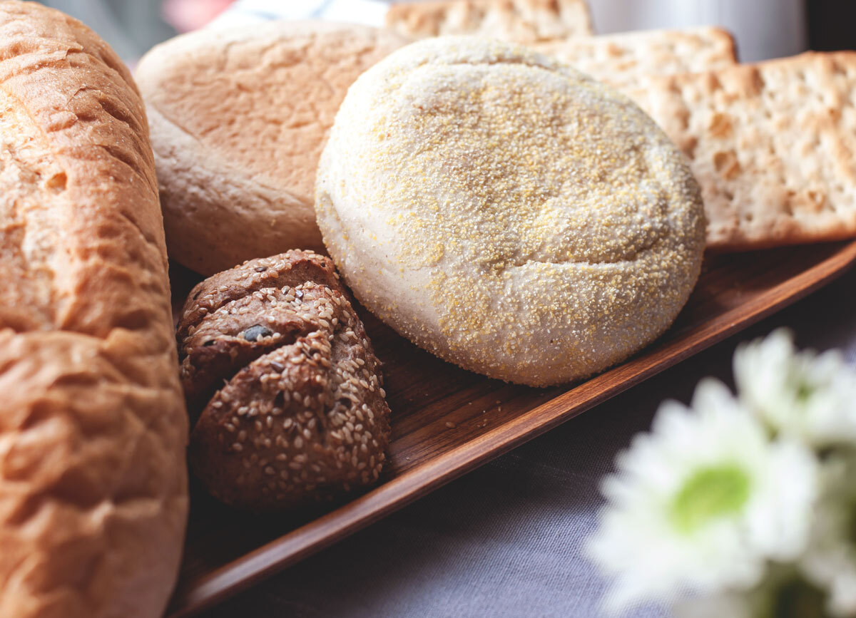 Loaf of bread seedy grain roll english muffin whole wheat crackers on wooden tray