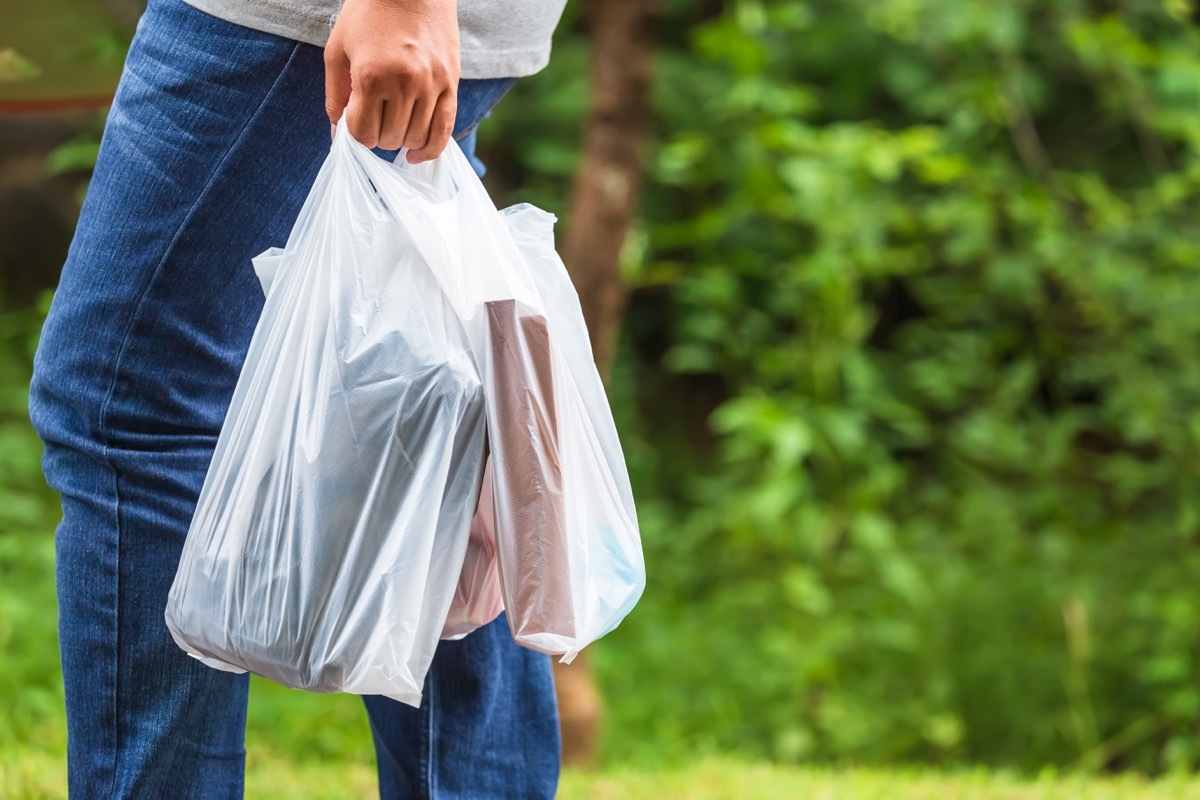 Woman hold the plastic bags and walk on the street in the park