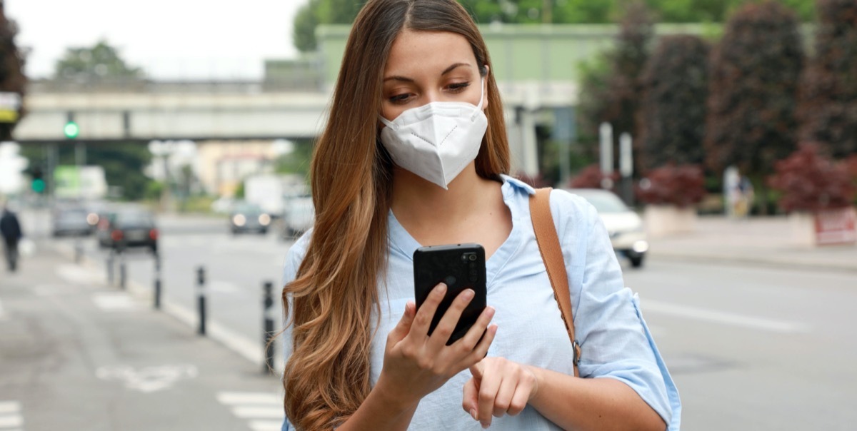 Woman holding phone on the street.