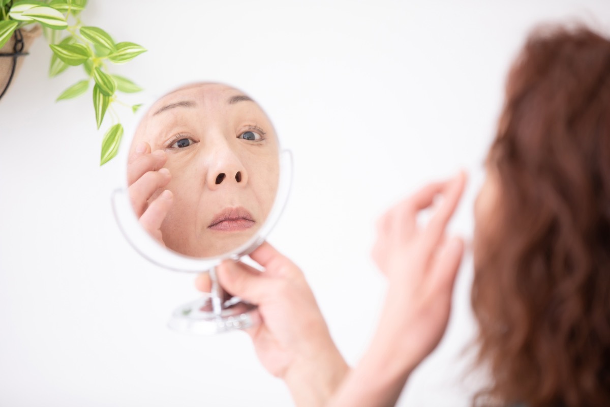 older asian woman applying eye cream