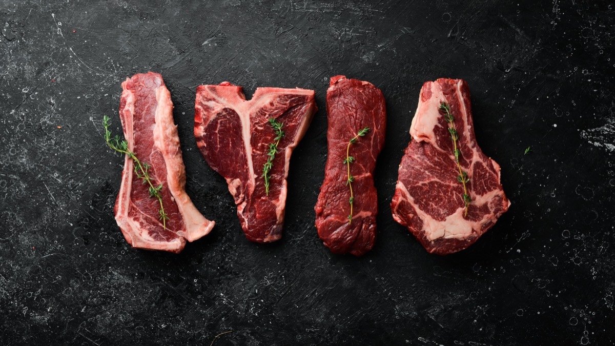 4 Raw Steaks on Black Board