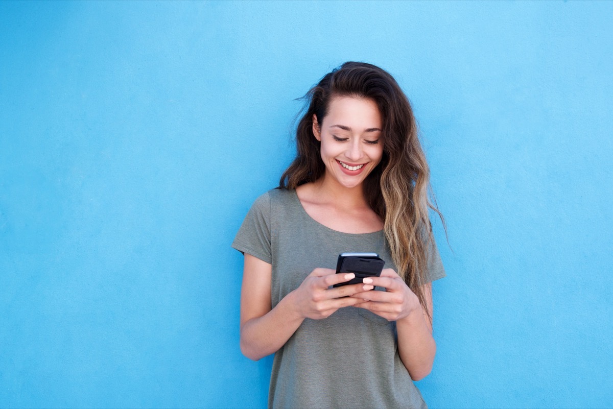 woman smiling while going through Tinder bios on her phone