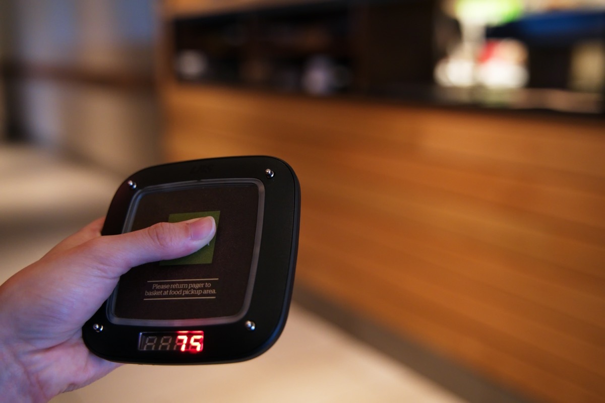 Restaurant customer waiting for the electronic guest pager to notify of an order status.