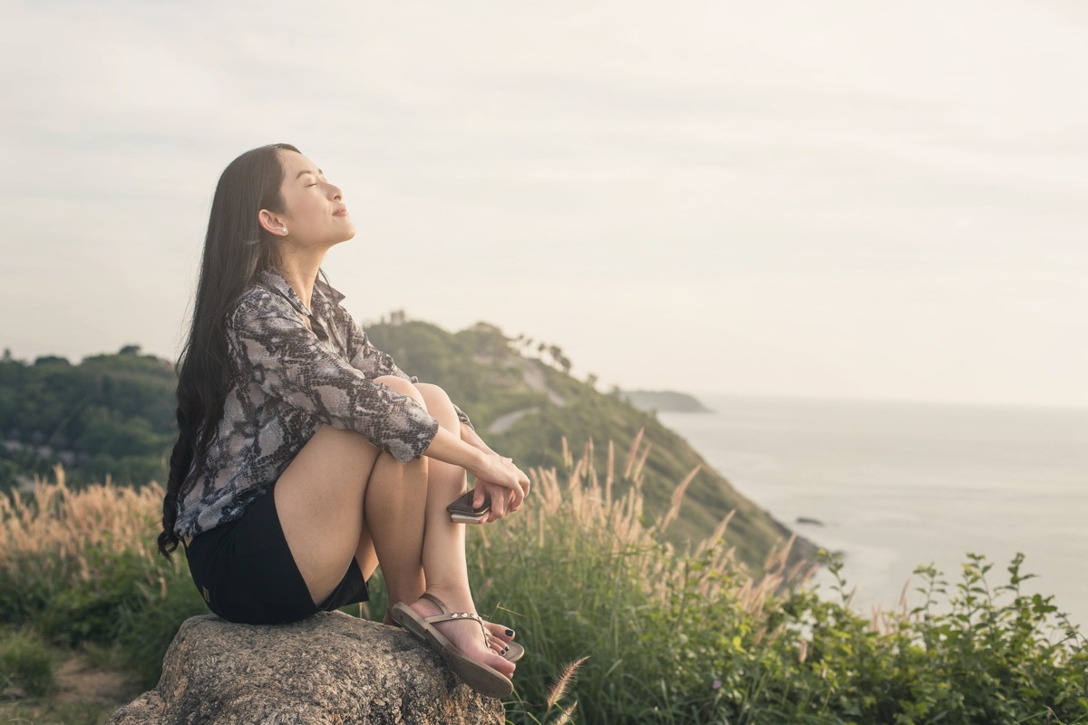 relaxed woman sitting in the grass by the ocean