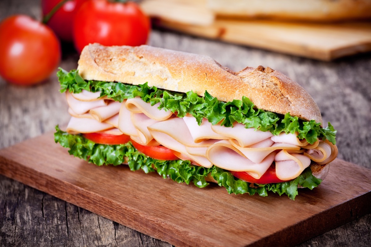 turkey sandwich, wooden board, lettuce, tomato