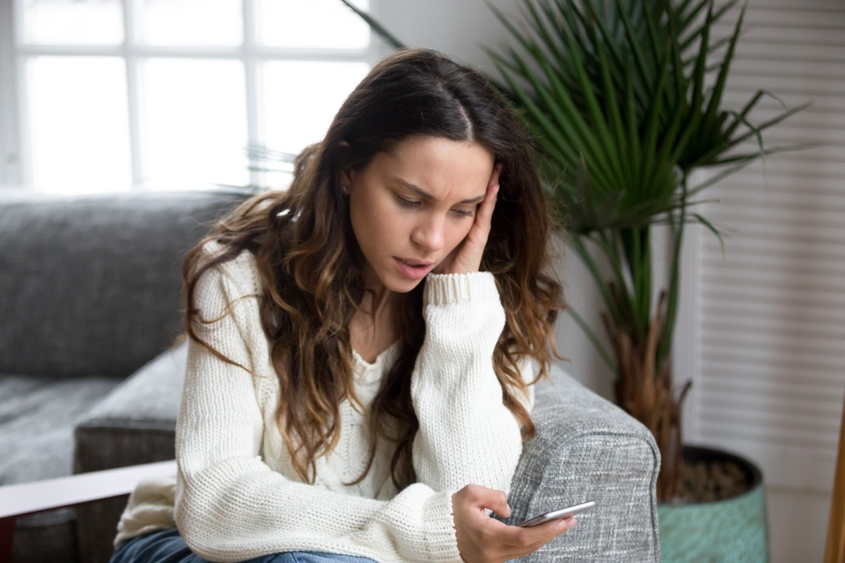 Woman reading phone looking negatively at news