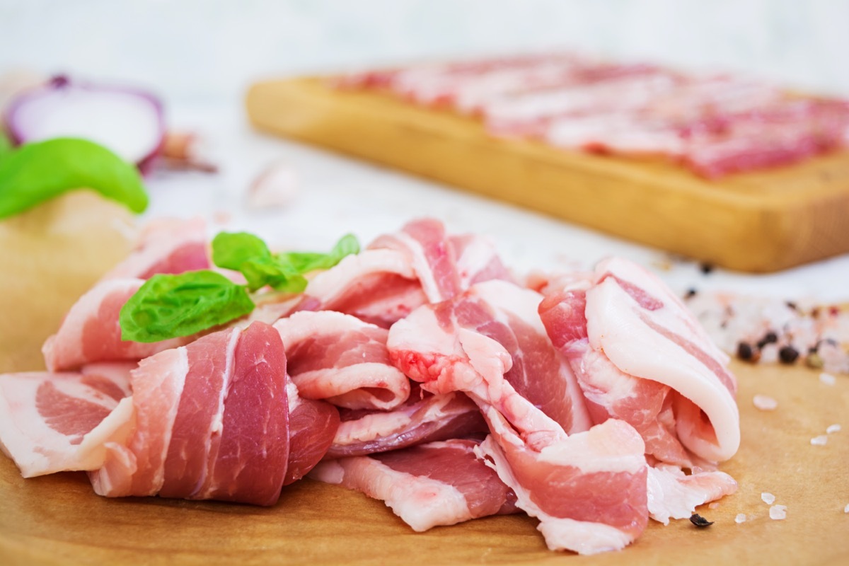 Fresh sliced bacon with spices on white background