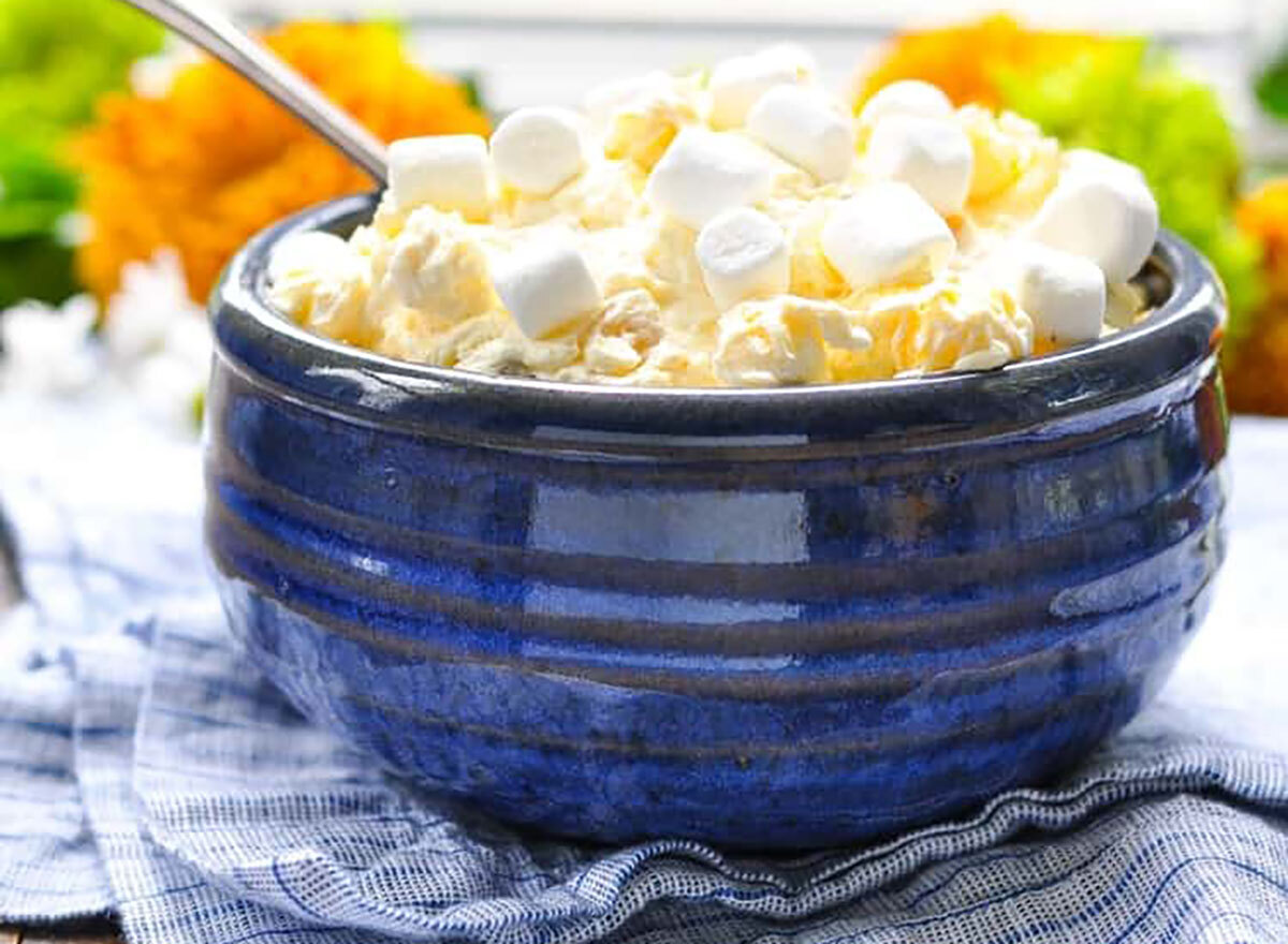 pineapple orange fluff salad topped with marshmallows in blue bowl