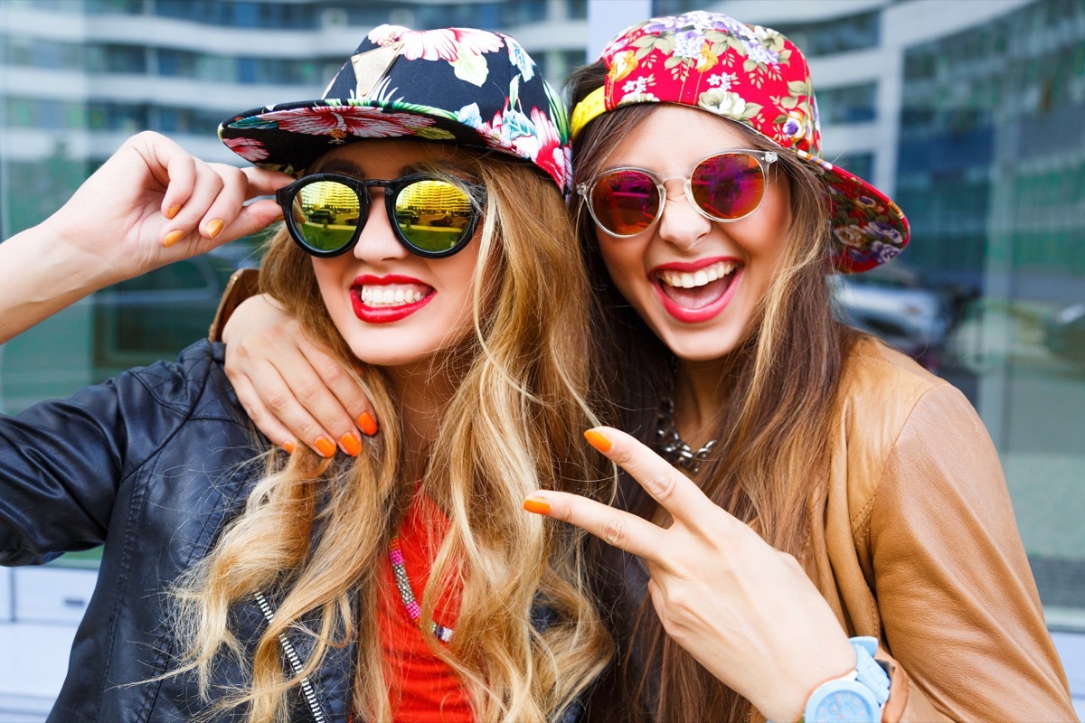 Two women wearing floral straight cap hats with sunglasses