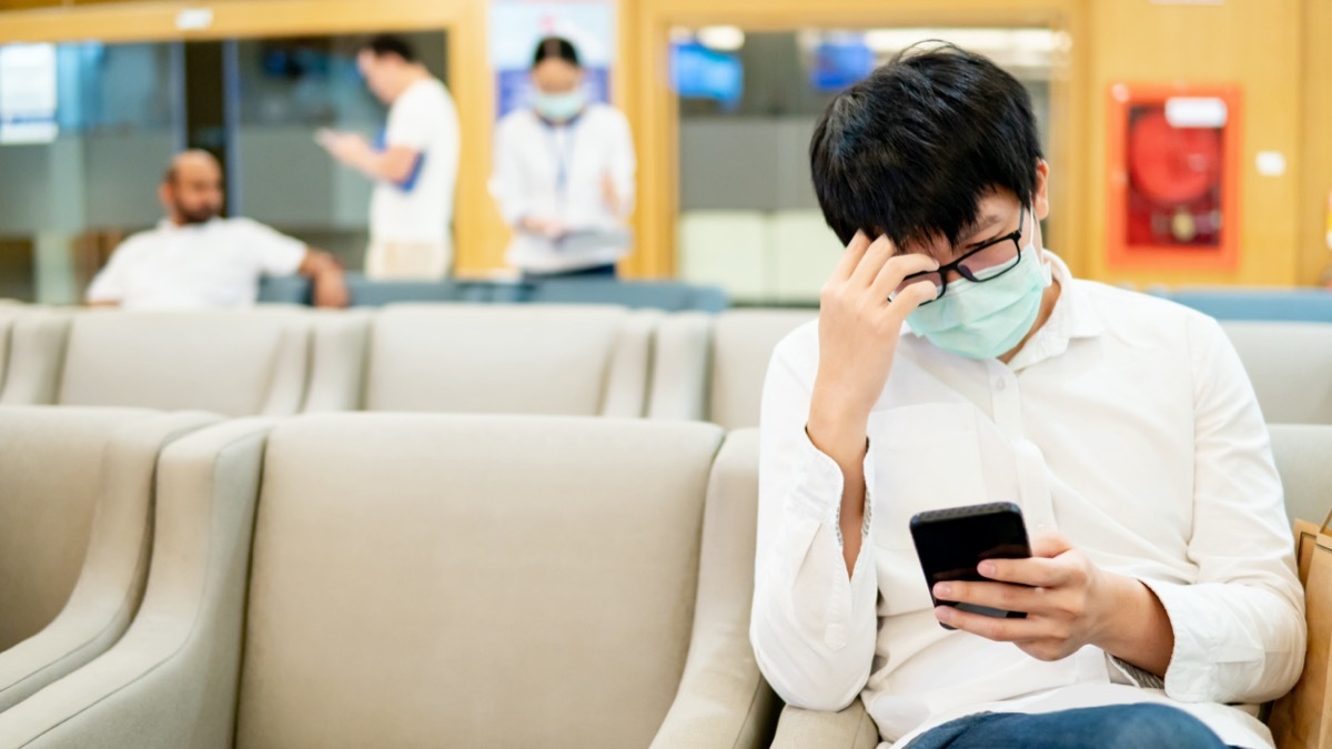 patient wearing surgical mask using smartphone in hospital or medical center. Medical exam or body check up.