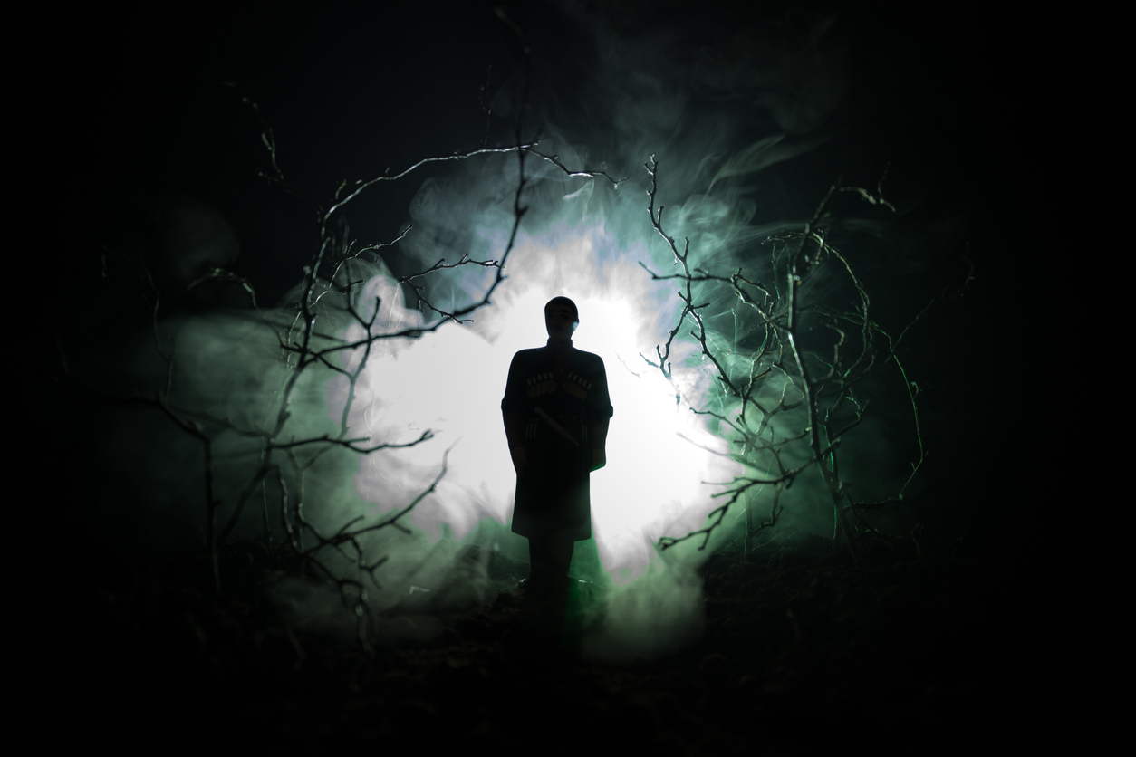 strange silhouette in a dark spooky forest at night, mystical landscape surreal lights with creepy man