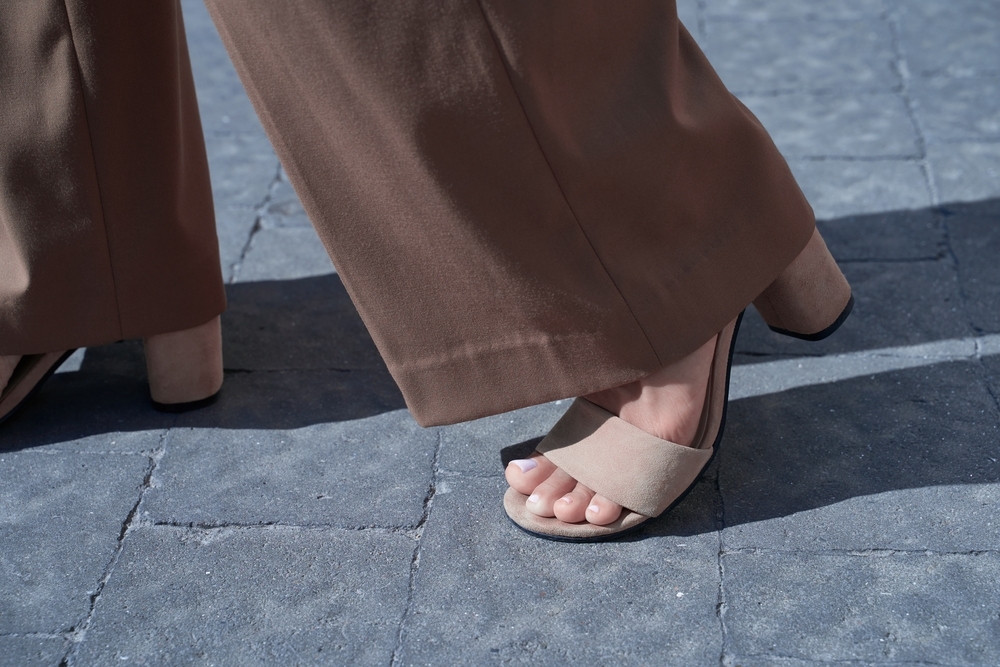 Close up of woman wearing brown bell bottom flare pants and heeled sandals