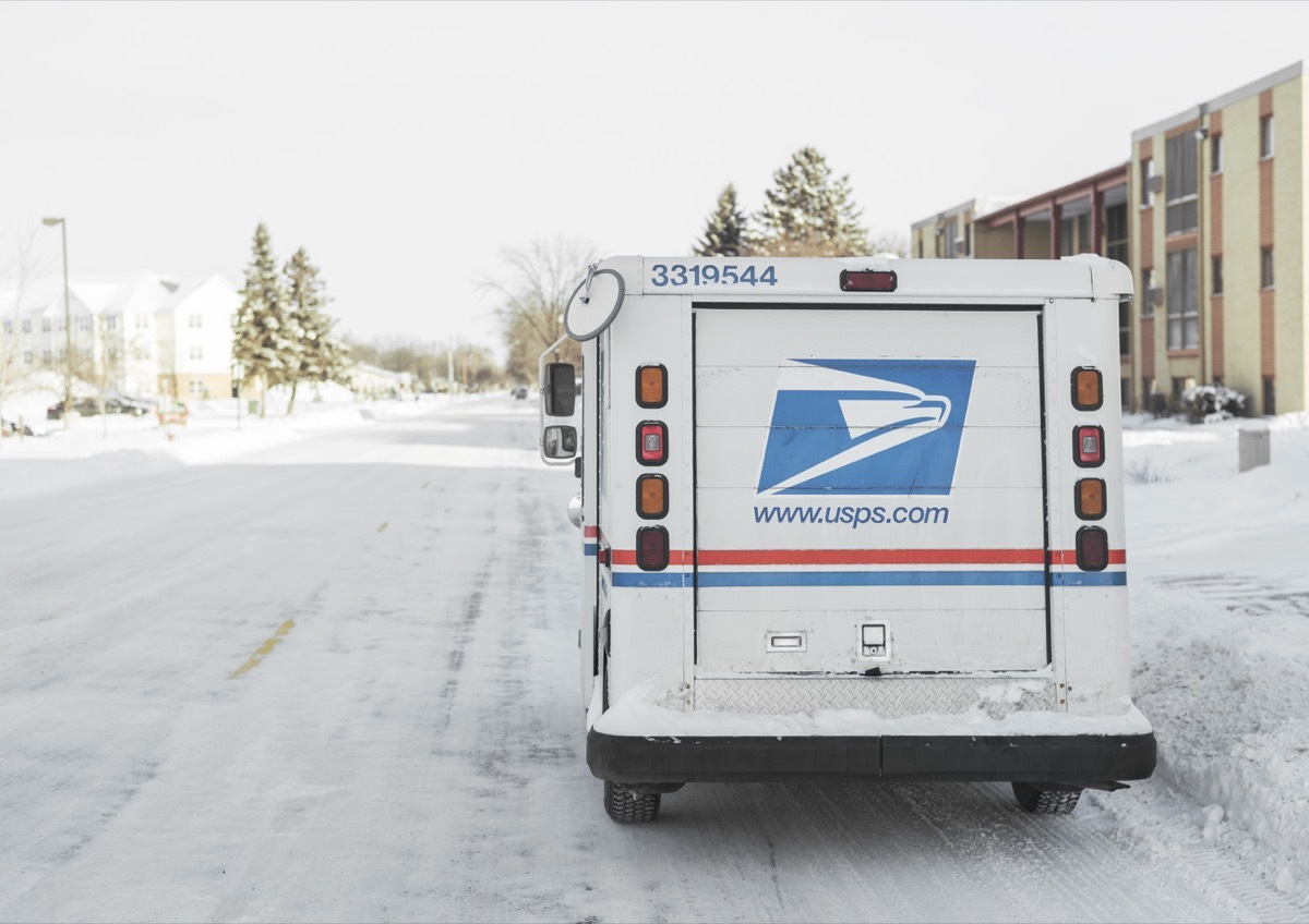 USPS, United States Postal Service, van parked on suburban street during winter with lots of snow.