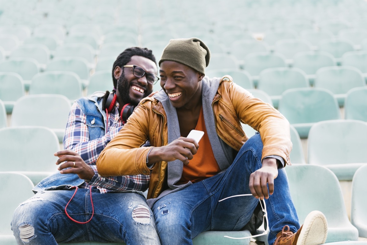 friendship quotes: two friends laughing in an empty stadium