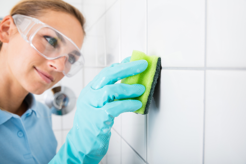 Woman cleaning the grout on the tile walls