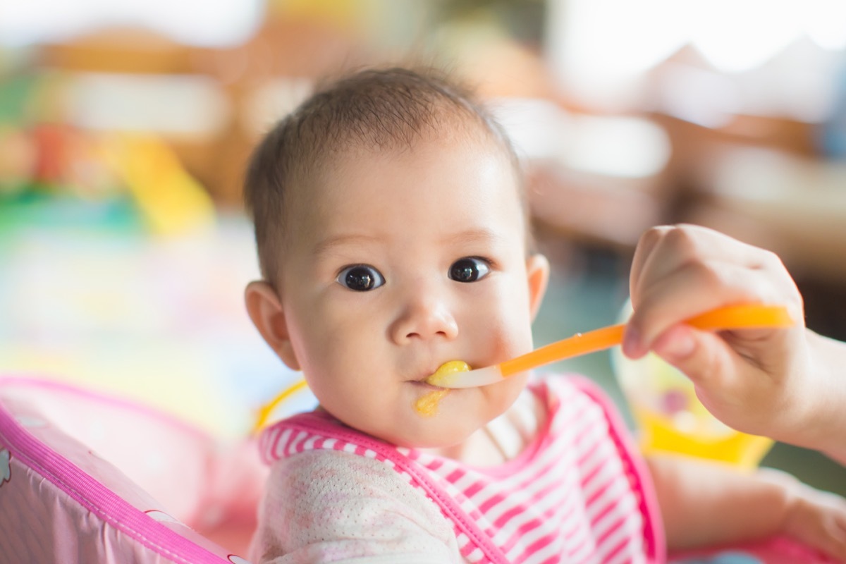 asian baby being fed in pink bib