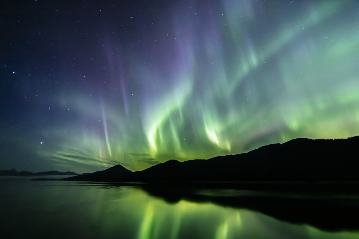 The Northern Lights in the sky above hills on a coastline