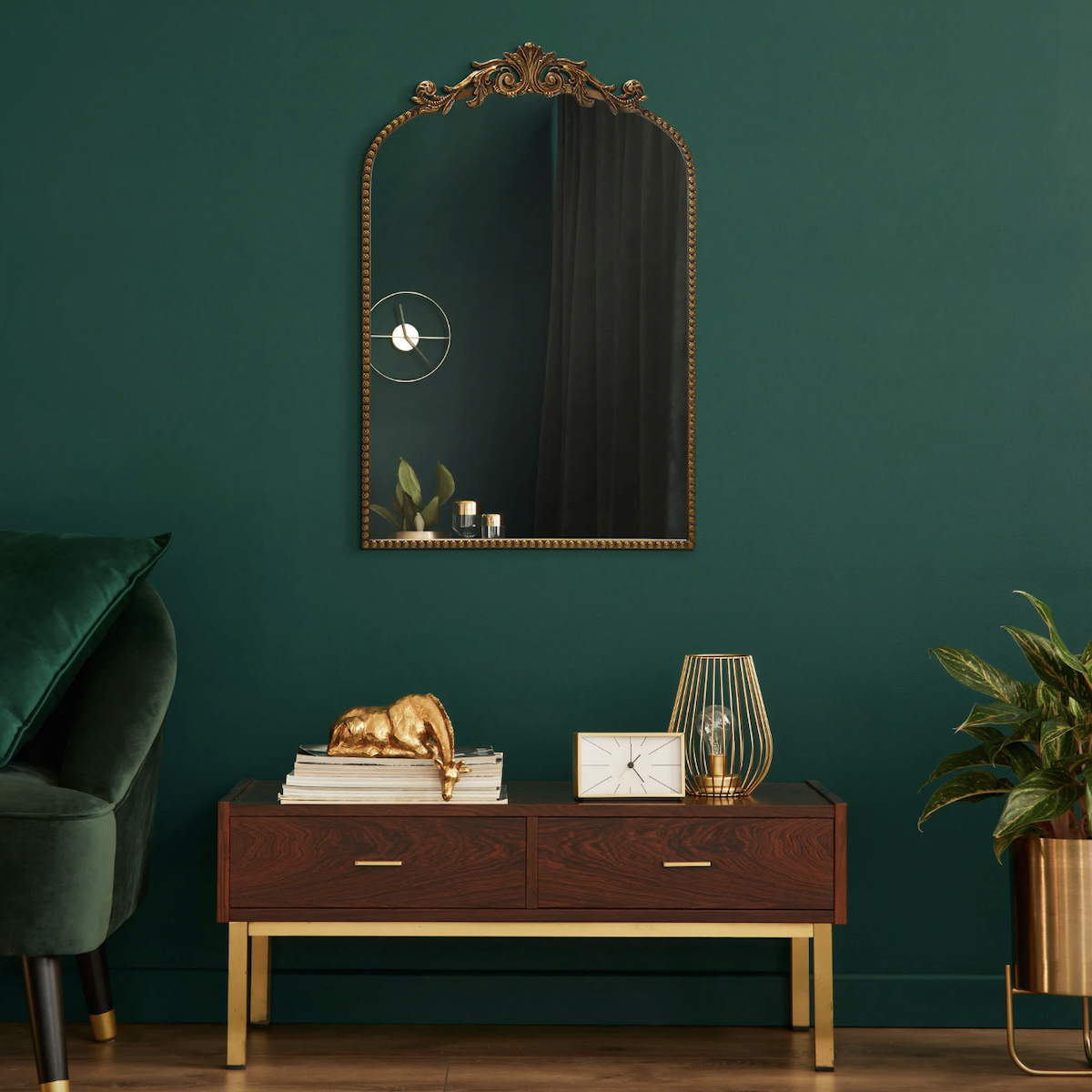 Styled product shot of a gold mirror from Walmart, set on an emerald green wall 