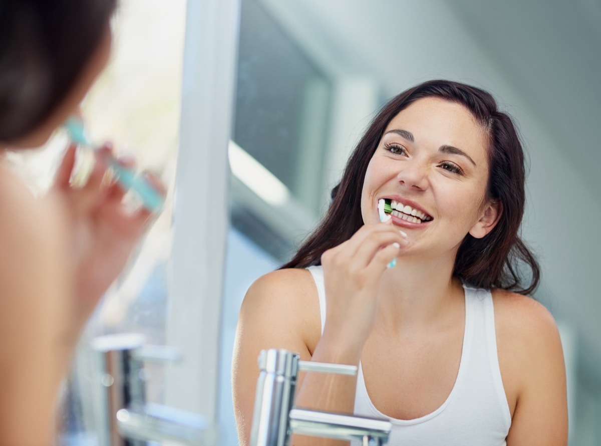 Shot of an attractive young woman brushing her teeth in the bathroom at home