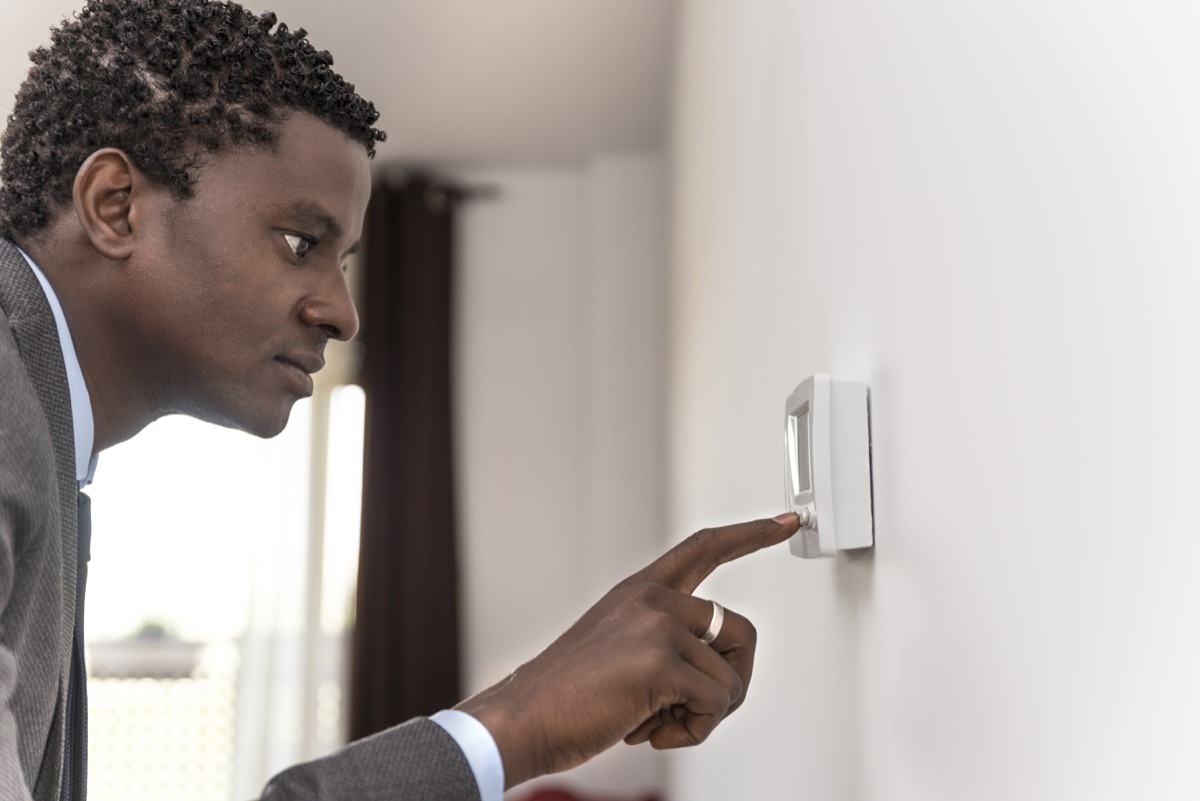 middle aged black man using thermostat