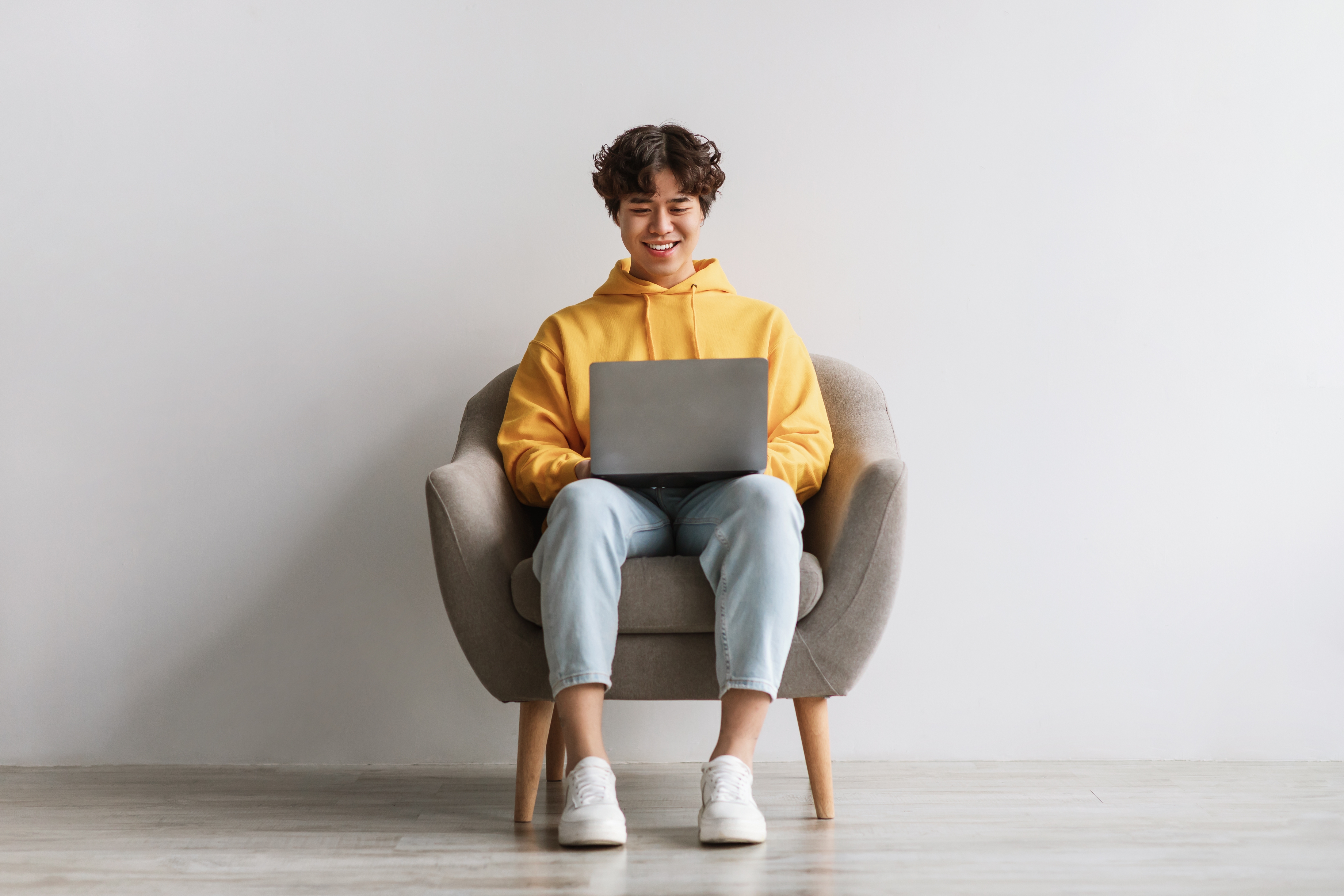 Young man sitting in chair and working on laptop