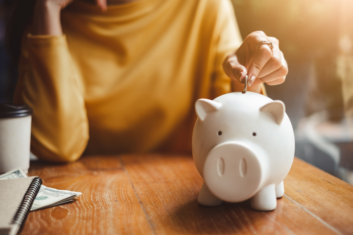 Woman putting money in piggy bank for retirement