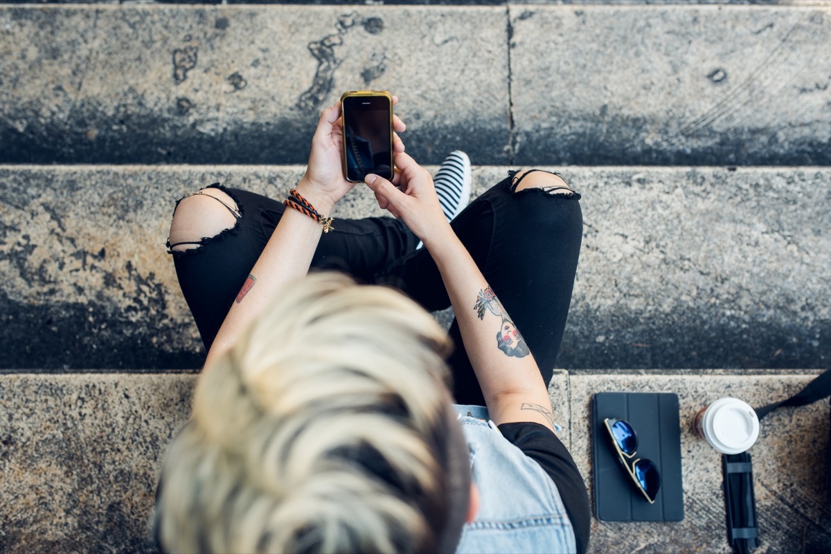 woman with short blonde dyed hair and tattoos reads text message, craziest things brides and grooms have ever done at weddings