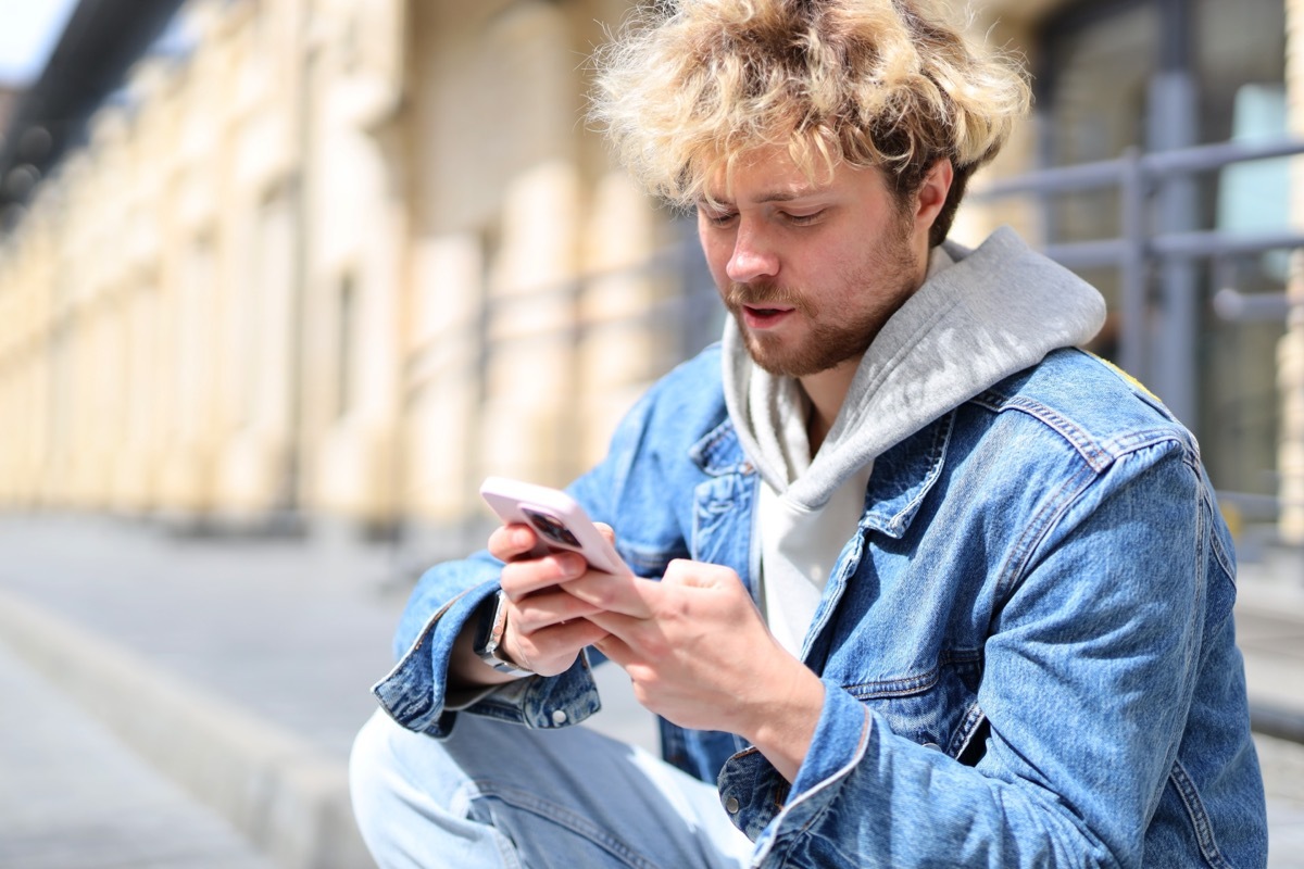 man sitting on the curb reading a 