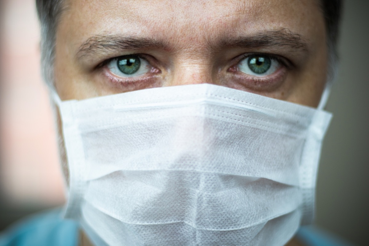 Close-up middle-aged green-eyed doctor with mask on his face