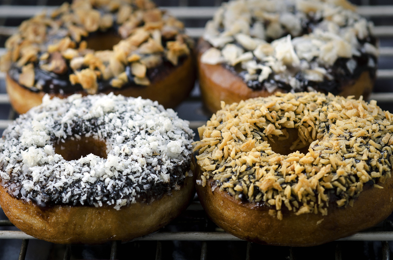 Two Chocolate Donuts in front of focus and, two in back out of focus. with Coconut Topping. Toasted and white on top.