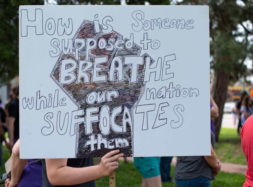 2BW98M9 Manhattan, Kansas, USA. 30th May, 2020. A peaceful protester holds a sign which reads, How is Someone supposed to Breathe while our nation suffocates them, on Saturday in response to the death of George Floyd by Minneapolis police earlier this week. The peaceful protesters marched from Triangle Park to Juilette Avenue and was organized by Pastor JahVelle Rhone and Trumanue Lindsey. Credit: Luke Townsend/ZUMA Wire/Alamy Live News