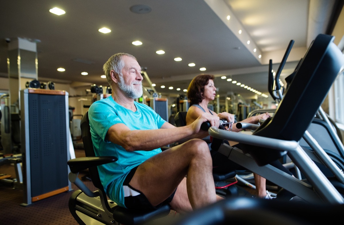 Beautiful fit senior couple in gym doing cardio work out.